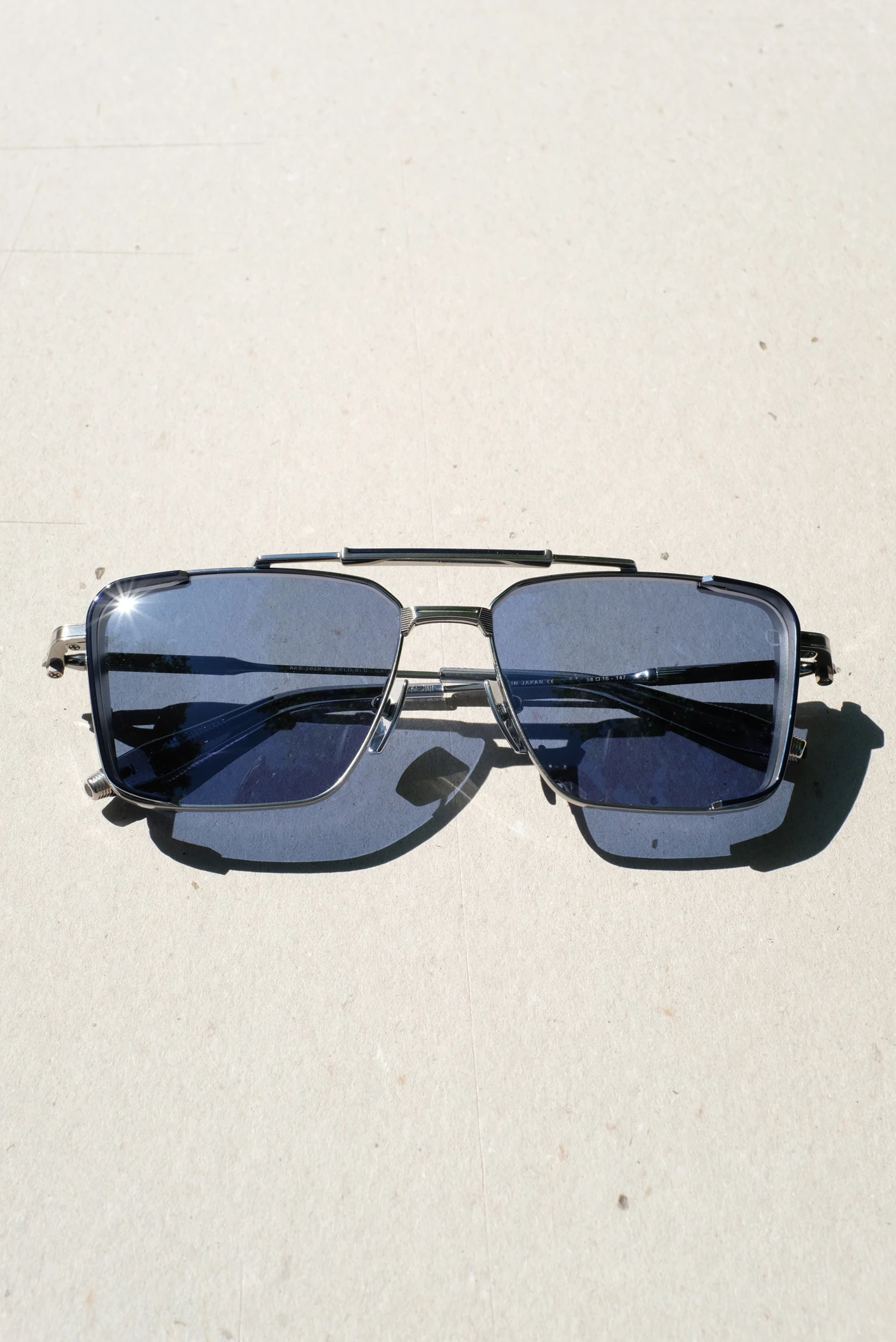 Akoni Hera sunglasses, aviator style frame made of black/silver titanium palladium and with blue lenses. Made in Japan.